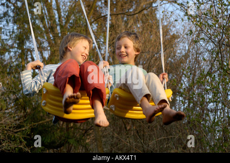 Eight-year-old and ten-year-old boys swinging happy Stock Photo