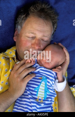 Happy father sleeps with newborn baby on a blue blanket Stock Photo
