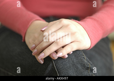 Folded hands resting on a lap. Stock Photo