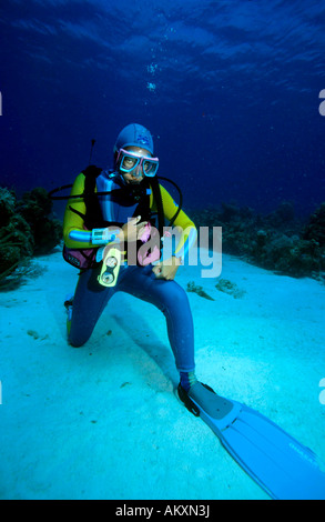 Underwater sign language ' has a cramp ', diver points with the fist at the part of the body where the cramp is. The Caribbean. Stock Photo