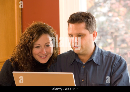 Husband and wife working on home laptop computer. Stock Photo