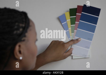 A  woman holds up color swatches to a wall. Stock Photo