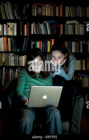 10 year old girls with a laptop computer in front of a bookshelf