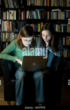 10 year old girls with a laptop computer in front of a bookshelf
