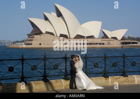 Sydney Opera House with bride and groom having their wedding photos taken in front of it. Bennelong Point. Sydney. AUSTRALIA. Stock Photo