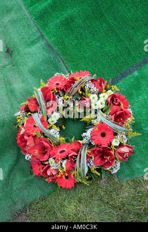Wreath lying on artificial matting beside newly dug grave Wales UK Stock Photo