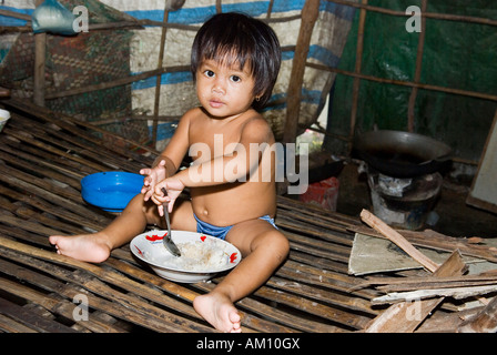 Boy eating rice in a hut in Andong slum area, Phnom Penh, Cambodia Stock Photo