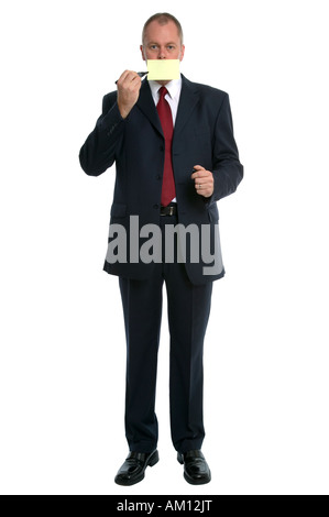 Businessman with a blank yellow adhesive note over his mouth holding a pen Stock Photo