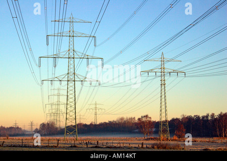 Power poles - high voltage electrical power lines - sunrise at winter morning - Schleswig-Holstein, Germany, Europe Stock Photo