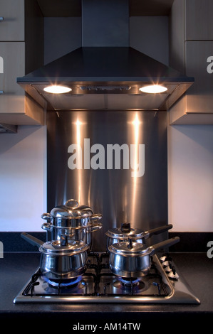 Moderm kitchen brushed steel gas hob and overhead extractor fan pots and pans cooking away Stock Photo