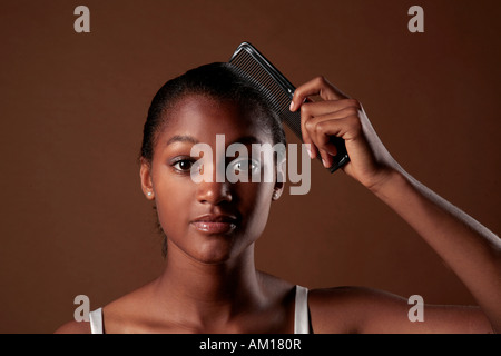 Young dark-skinned woman combing her hair Stock Photo