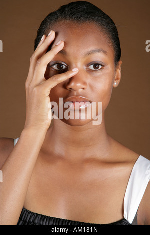 Young dark-skinned woman putting hand at her face Stock Photo