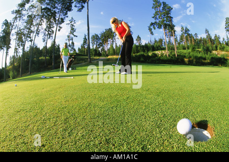 Two women putting on golf course in Sweden Stock Photo