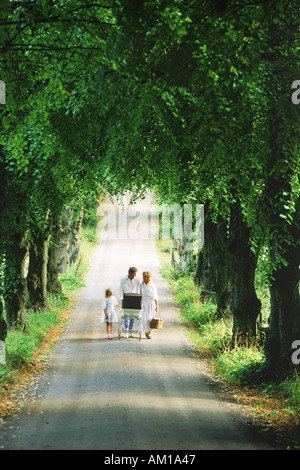 Family of four on tree lined country road in Sweden Stock Photo