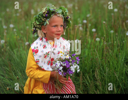 Young Swedish girl in traditional Midsummer dress collecting wild flowers Stock Photo