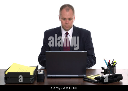 Businessman sat at his desk using a laptop computer Stock Photo