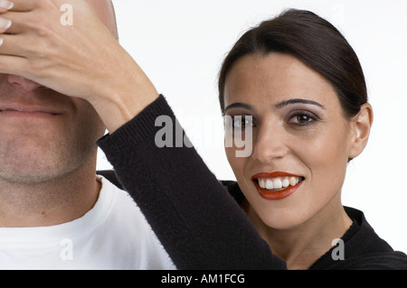 A woman holds her hands over the eyes of the man Stock Photo