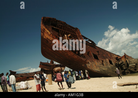 People stand on the beach by the Ship graveyard and rusting tankers on the beach in Beira. Mozambique, Southern Africa Stock Photo