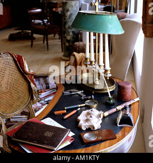 Antique leather-topped table with assortment of stationery and objects scattered across it Stock Photo