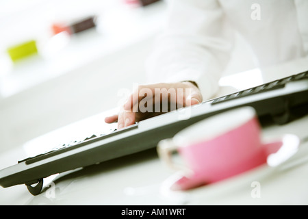 Mans hand on computer keyboard in light white office Stock Photo