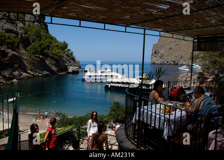 Restaurant overlooking port in Sa Calobra with high rocky mountains going down to the sea north coast of Mallorca Spain Stock Photo