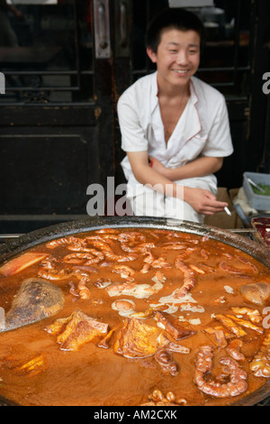 Boy sitting behind food on sale in hutong Beijing China Stock Photo