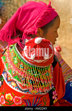 Young Flower Hmong mother carrying baby on back at Bac Ha in northern Vietnam Stock Photo
