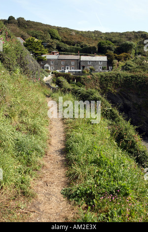 Coastal footpath leading to cottages on the cliffs in the small fishing village of Portloe in Cornwall UK Stock Photo