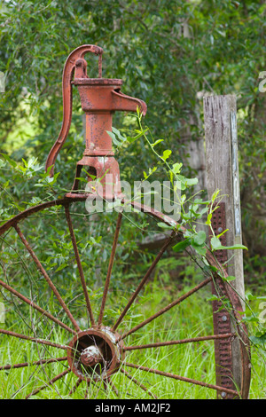 Entrance decoration consisting of antique well pump and wagon wheel Stock Photo