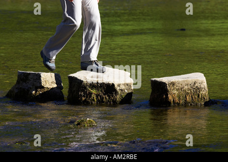 crossing three stepping stones in a river dovedale peak district national park uk Stock Photo