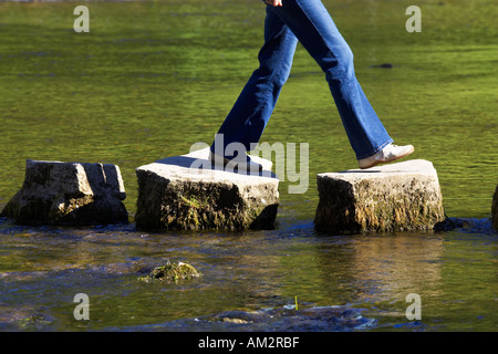 crossing three stepping stones in a river dovedale peak district national park uk Stock Photo