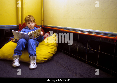 Young boy reading book in corner on big pillow. Stock Photo