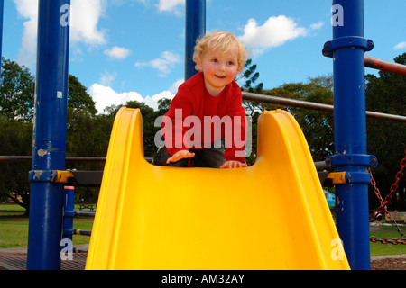 infant boy at top of slide in playground Stock Photo