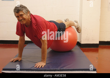 Older man doing push ups with exercise ball Stock Photo