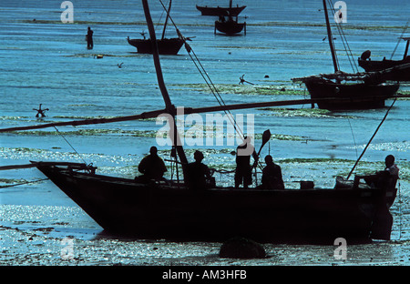 Silhouetted dhow with crew of fishermen Low tide Nungwi Unguja Zanzibar Tanzania Indian Ocean East Africa Stock Photo