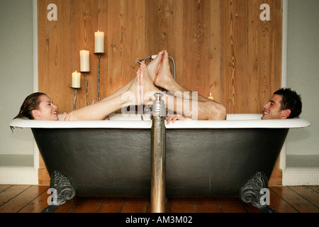 Couple in roll top bath pushing their feet together Stock Photo