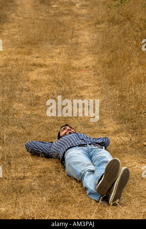 Young man laying in field alone Stock Photo