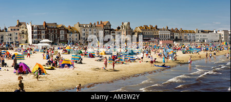 At a British seaside beach in summer, Weymouth beach, Dorset, England, UK - Panorama - people sunbathing and swimming Stock Photo