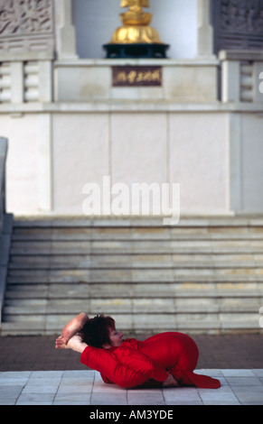 Carol Smith Yoga Teacher doing Surya Namaskar Sun Salutations in front of the Milton Keynes Buddhist P Stock Photo