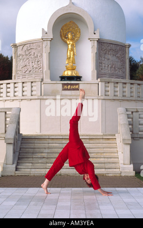 Carol Smith Yoga Teacher doing Surya Namaskar Sun Salutations in front of the Milton Keynes Buddhist Peace Pagoda Stock Photo