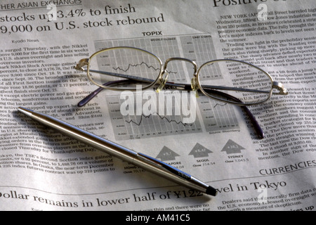Financial and business pages of a newspaper with glasses and silver pen Stock Photo