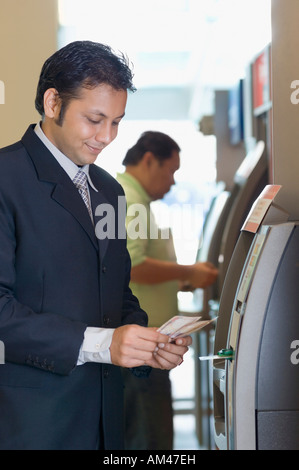 Businessman using an ATM at an airport Stock Photo