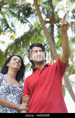 Low angle view of a young man pointing and young woman standing with arm in arm Stock Photo
