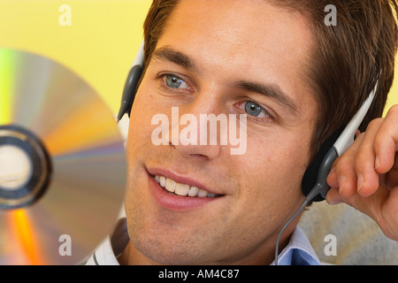 Man relaxing on sofa wearing headphones and holding compact disc  Stock Photo