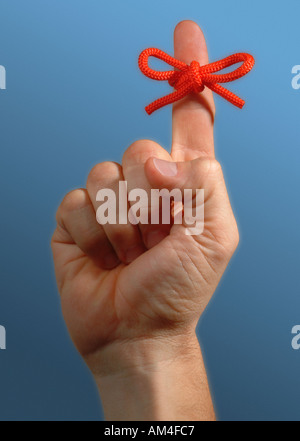 red string on finger tied in a large bow as a reminder Stock Photo