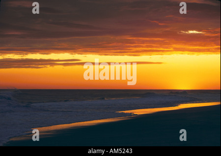 A golden sunset over a sandy ocean beach Stock Photo