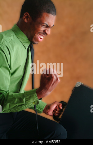 An African American business man with a brief case celebrates success by pumping his fist and smiling Stock Photo