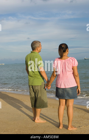 Rear view of a mid adult couple holding hands of each other on the beach Stock Photo