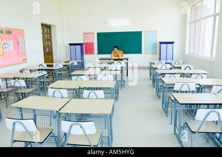 Female teacher sitting in an empty classroom Stock Photo - Alamy
