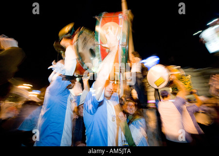 Musicians carry their bright drums high over the cheering and dancing crowd of fans, celebrating a 2-1 victory in the World Cup. Stock Photo